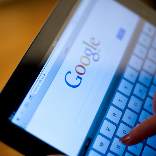 A pair of hands using a tablet with a search engine open on screen