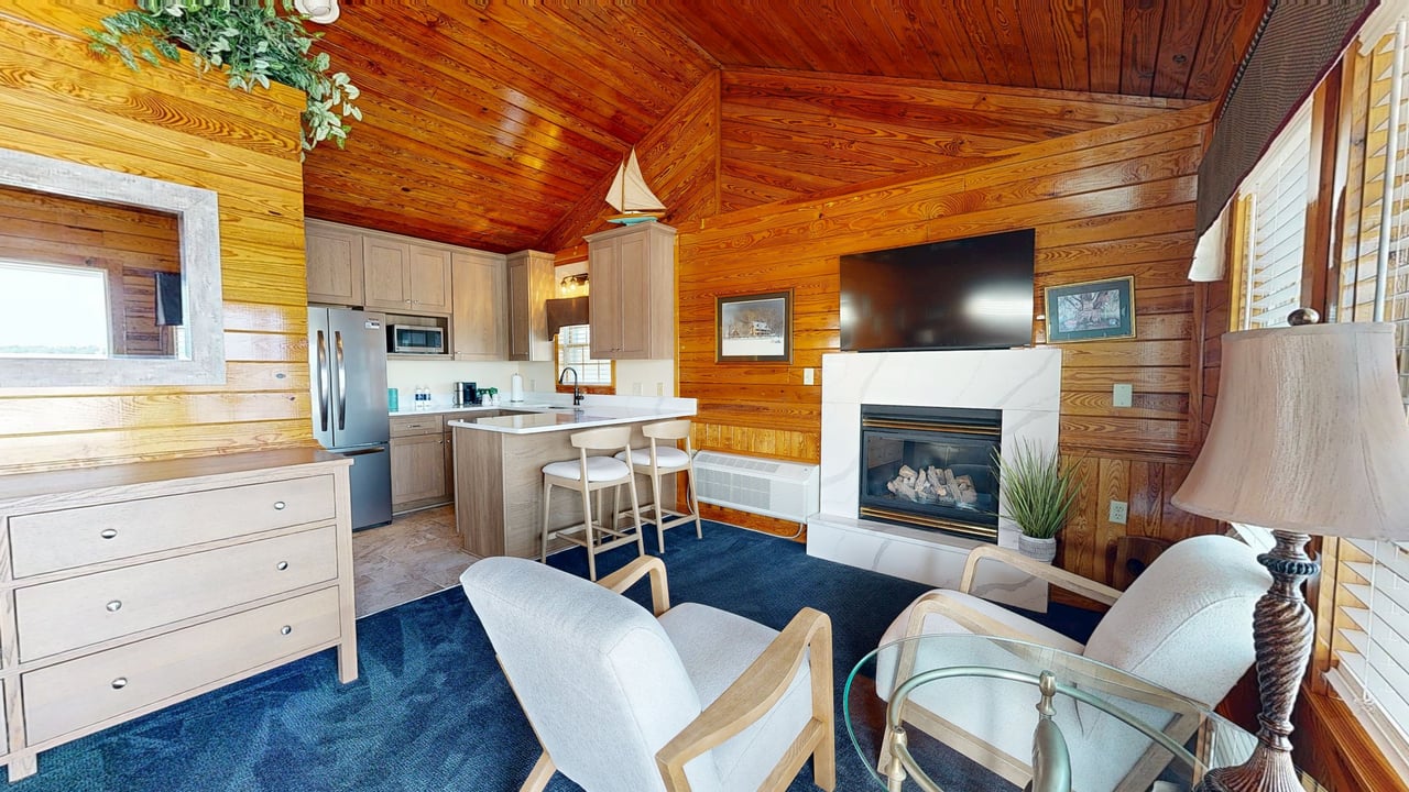 A pine-panelled cottage interior with a kitchenette, fireplace and vaulted wood ceiling